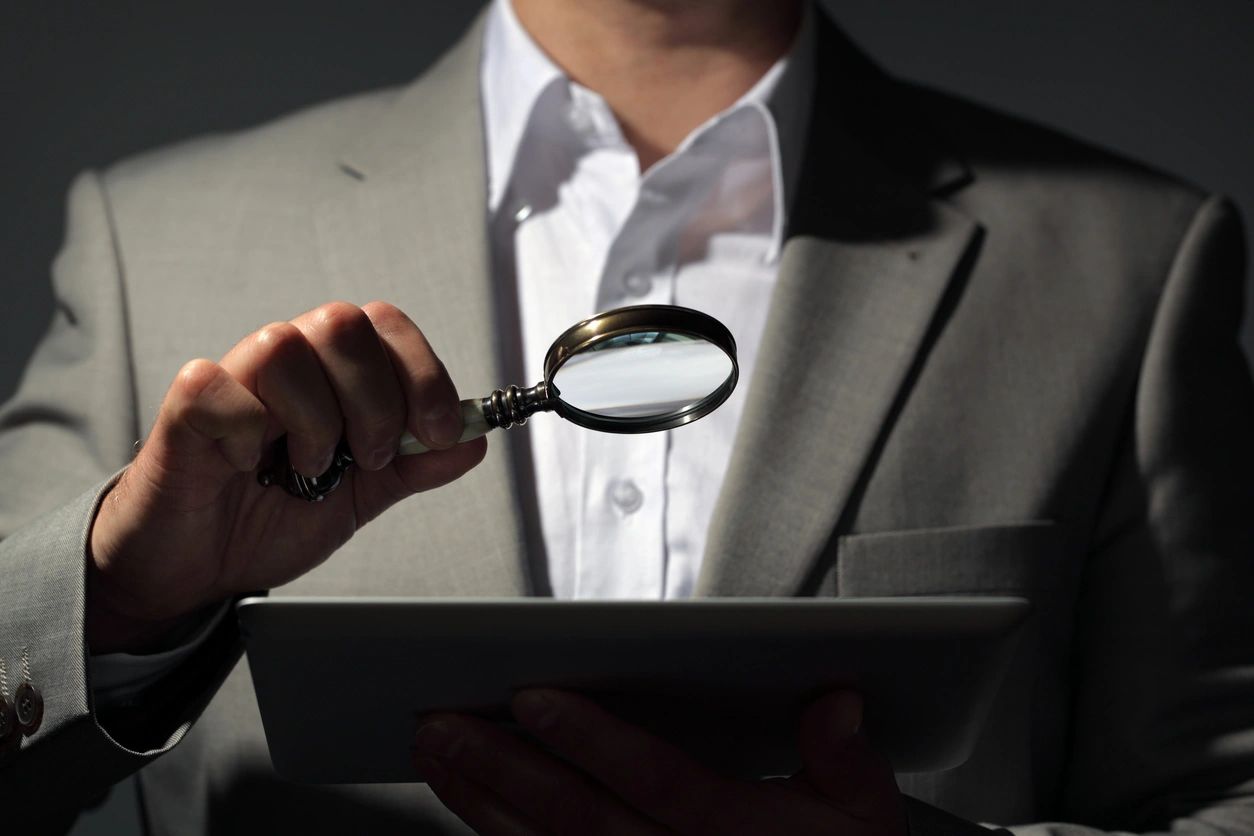 Businessman with magnifying glass and tablet